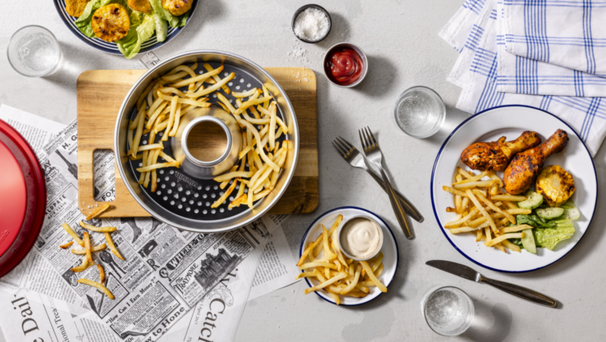 Plaque cuisson perforée Omnia avec des frites, présentée sur une table avec des assiettes de repas