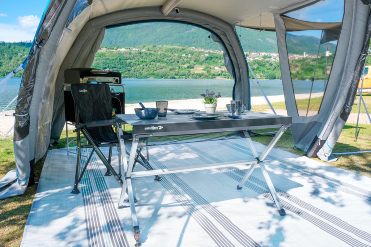 Table de camping Titanium Axia 4 dressée pour un repas sous un auvent au bord de l’eau