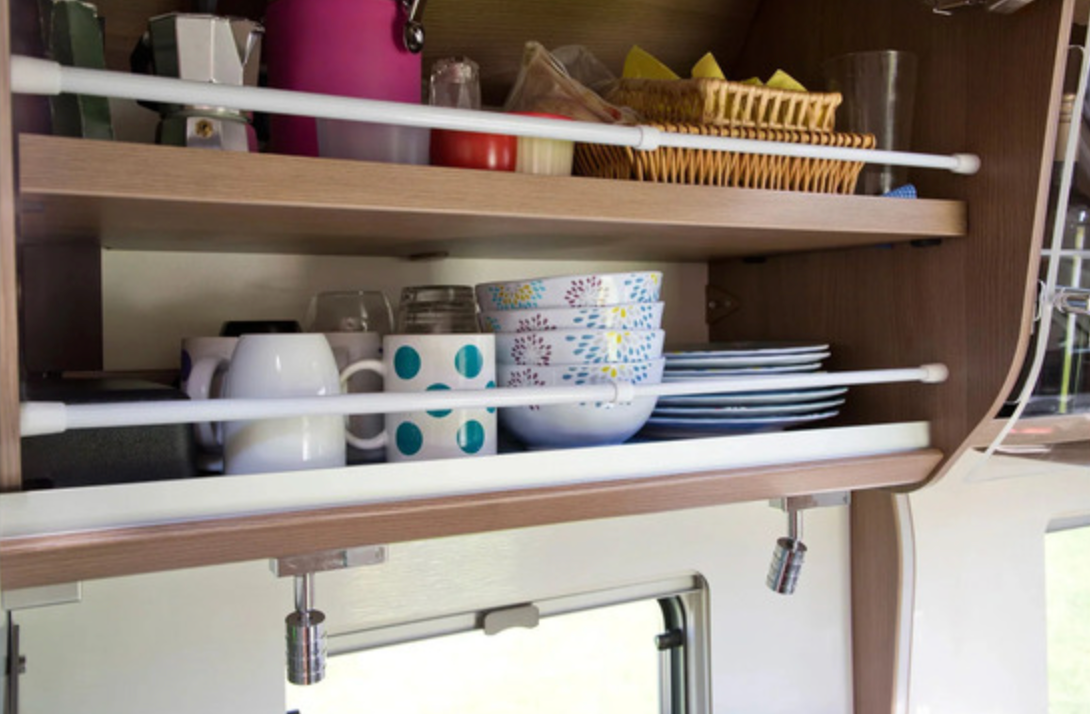 Retenue anti-chute grand modèle placée devant des tasses, bols et assiettes dans un placard de véhicule aménagé