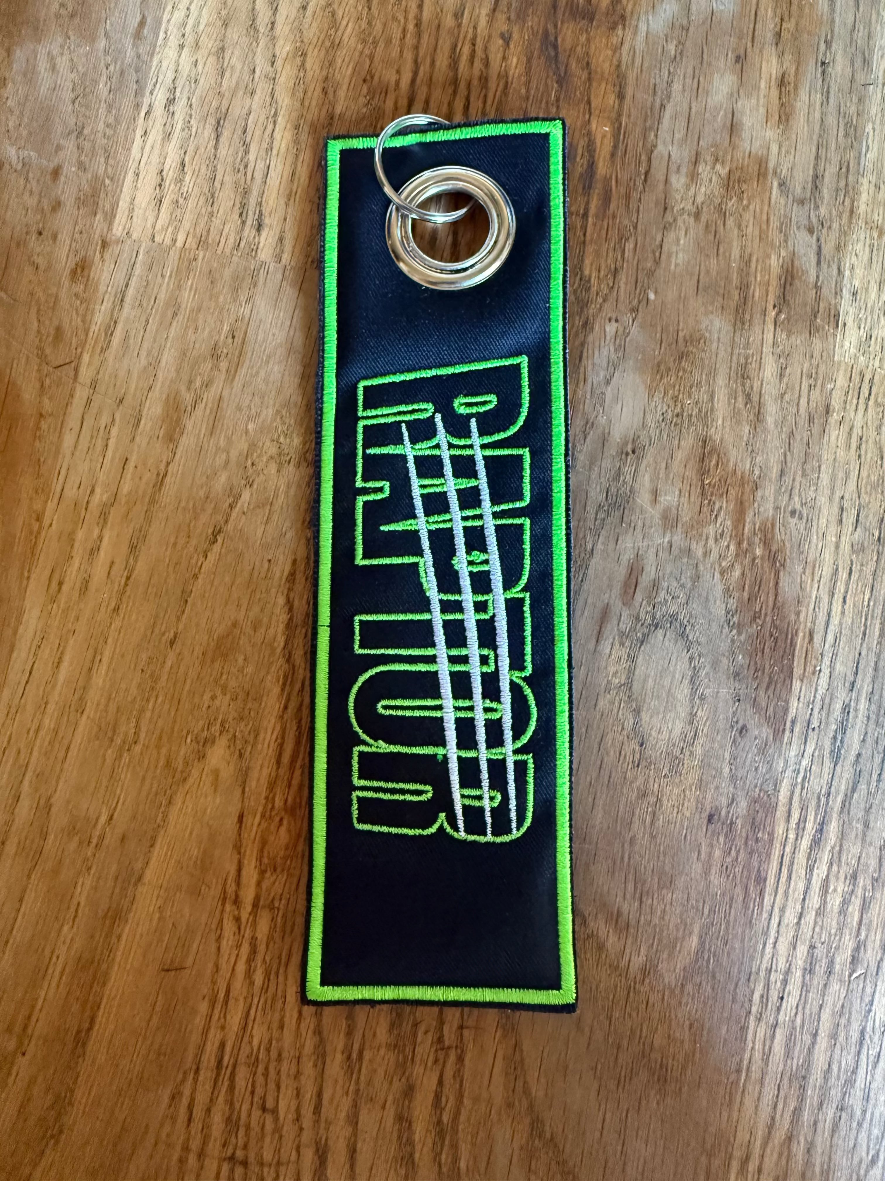 porte-clé brodé Raptor – recto/verso tissu noir lettrage vert